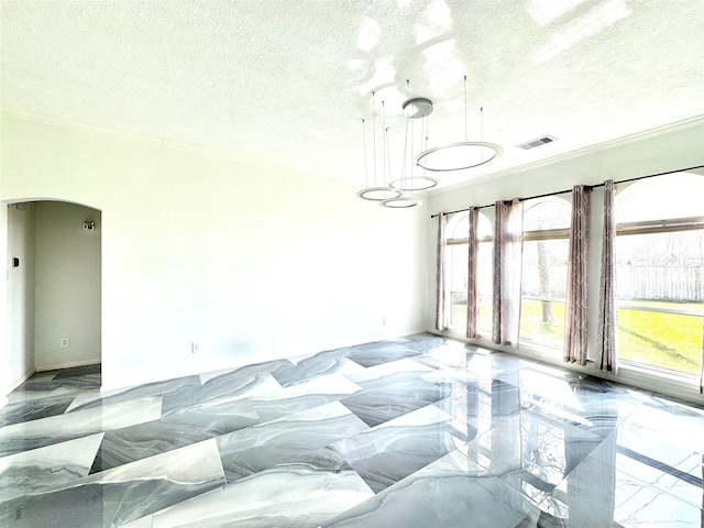 unfurnished room featuring visible vents, a textured ceiling, arched walkways, and a wealth of natural light