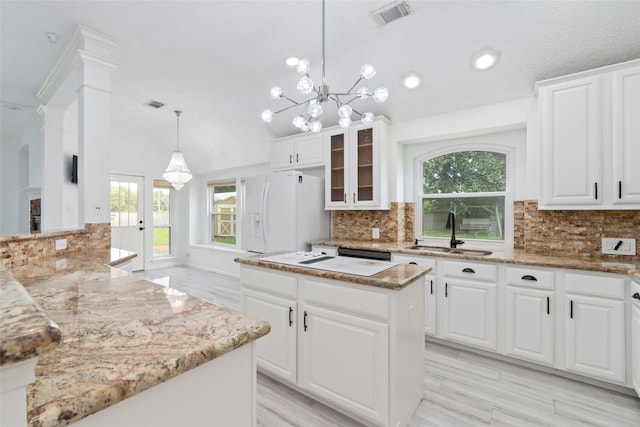 kitchen with visible vents, a kitchen island, glass insert cabinets, white fridge with ice dispenser, and a sink