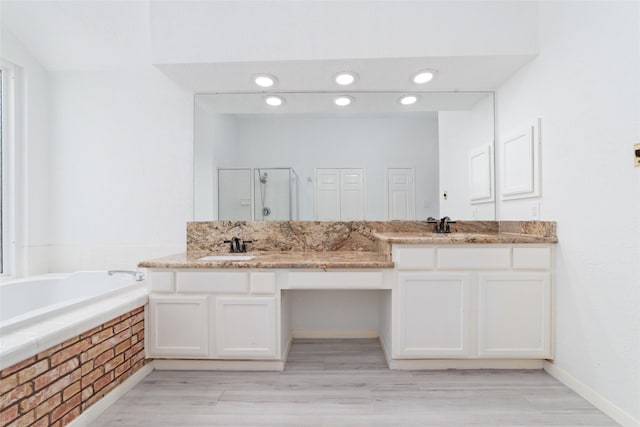 bathroom with a garden tub, a sink, a shower stall, and double vanity