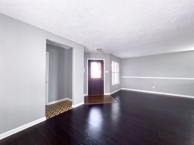 foyer entrance featuring a textured ceiling, wood finished floors, and baseboards