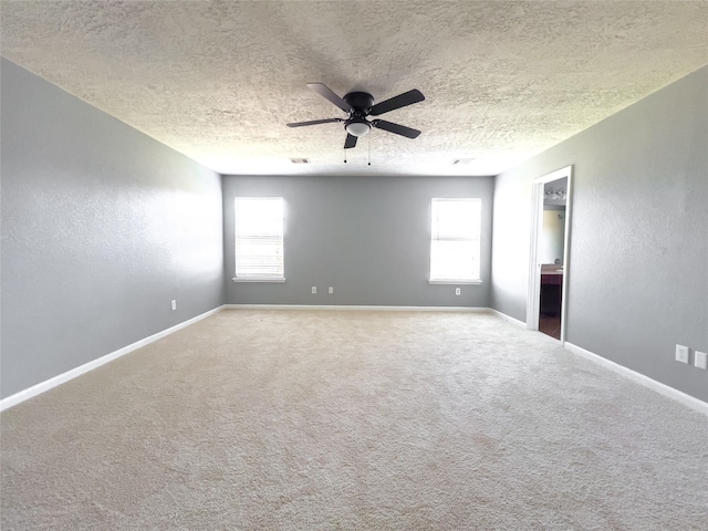 carpeted empty room with visible vents, baseboards, a textured wall, ceiling fan, and a textured ceiling