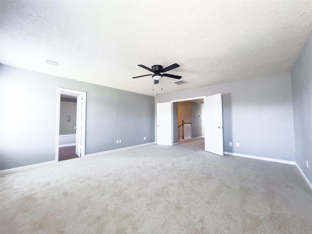 unfurnished bedroom with carpet, visible vents, a textured ceiling, and baseboards