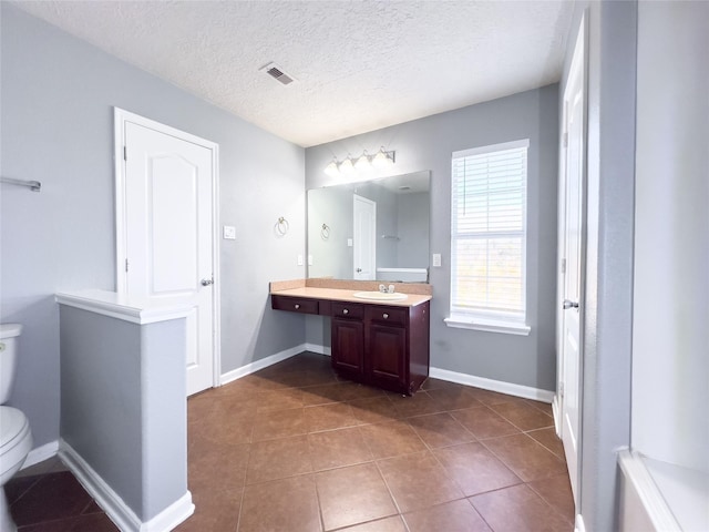 bathroom featuring baseboards, a textured ceiling, toilet, and tile patterned floors