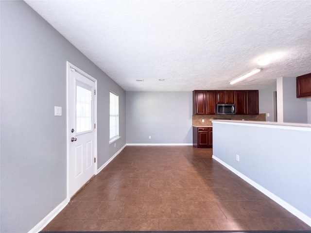 unfurnished living room featuring a textured ceiling and baseboards