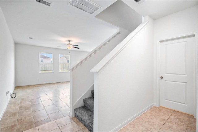 stairs featuring a ceiling fan, visible vents, baseboards, and tile patterned floors