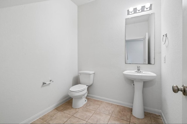 bathroom with baseboards, toilet, and tile patterned floors