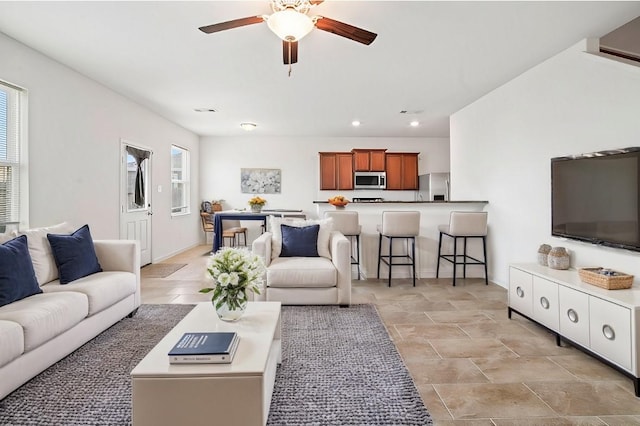 living room with a healthy amount of sunlight, baseboards, and a ceiling fan