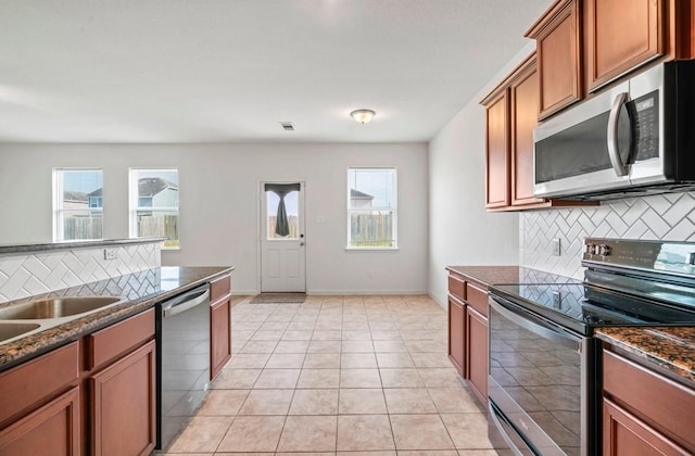 kitchen featuring stainless steel appliances, brown cabinets, light tile patterned flooring, and backsplash