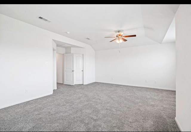 carpeted spare room featuring baseboards, visible vents, vaulted ceiling, and a ceiling fan