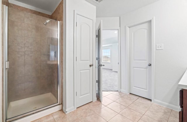 full bathroom featuring a stall shower, vanity, baseboards, and tile patterned floors