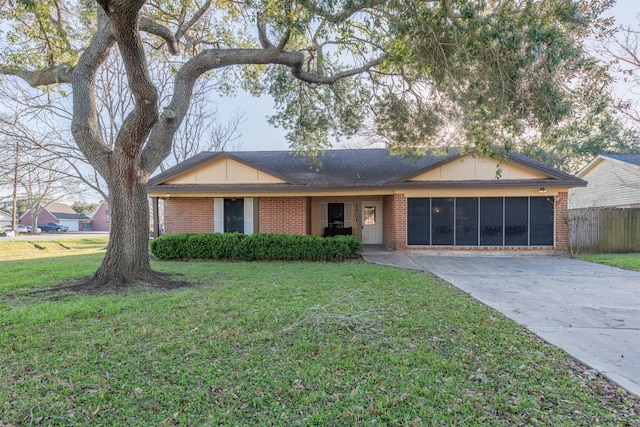 ranch-style home with driveway, fence, a front lawn, and brick siding