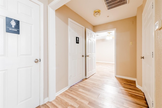 corridor featuring baseboards, visible vents, and light wood-style floors