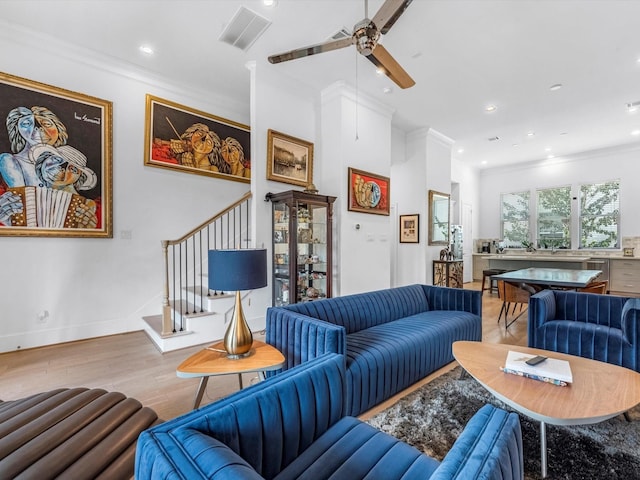 living area with visible vents, baseboards, light wood-style flooring, stairway, and ornamental molding