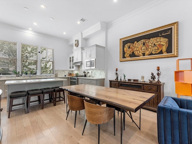 dining space with light wood-style floors, recessed lighting, visible vents, and ornamental molding