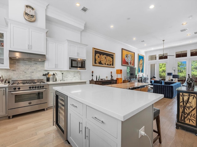 kitchen with visible vents, high end stainless steel range, built in microwave, light countertops, and under cabinet range hood