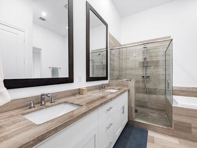 bathroom with double vanity, a stall shower, visible vents, and a sink