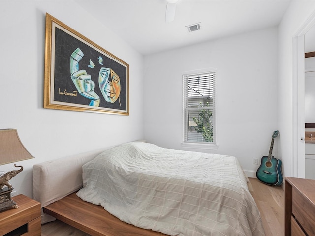 bedroom featuring wood finished floors, visible vents, and a ceiling fan