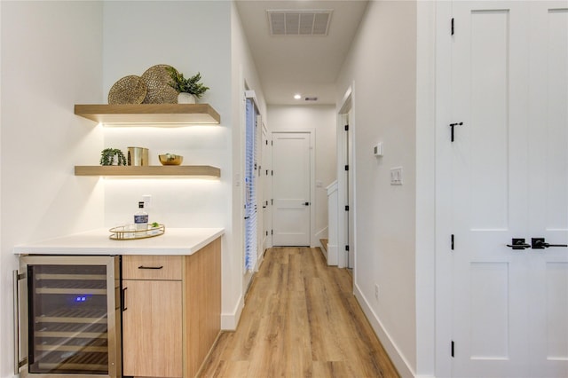 hall featuring wine cooler, light wood-style flooring, visible vents, and baseboards