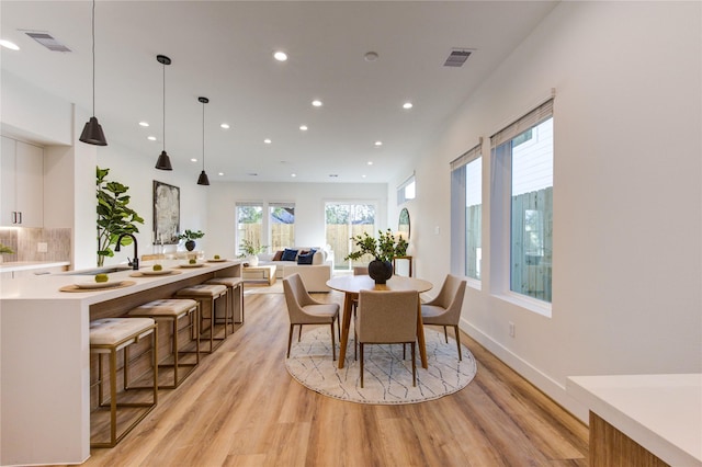 dining area with baseboards, light wood-style flooring, visible vents, and recessed lighting