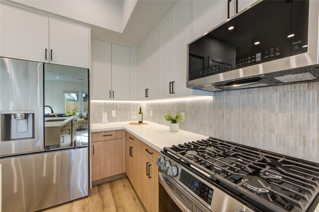 kitchen with light wood finished floors, tasteful backsplash, appliances with stainless steel finishes, light countertops, and light brown cabinets