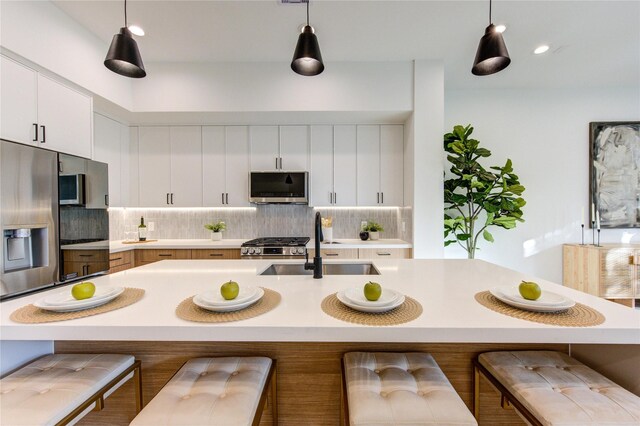 kitchen with stainless steel appliances, backsplash, a sink, and light countertops