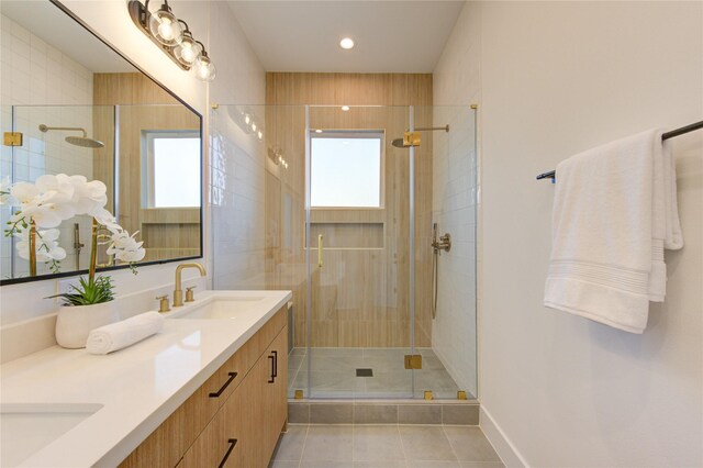 full bathroom with double vanity, a stall shower, baseboards, tile patterned flooring, and a sink