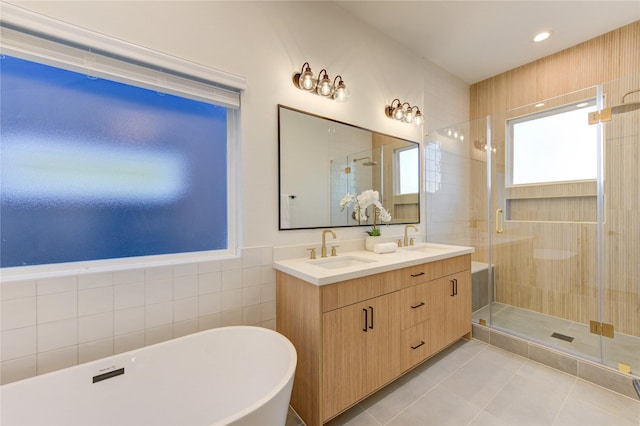 bathroom with double vanity, a stall shower, tile patterned floors, a freestanding tub, and a sink