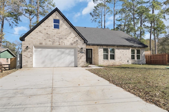 view of front of home featuring brick siding, a front yard, fence, a garage, and driveway