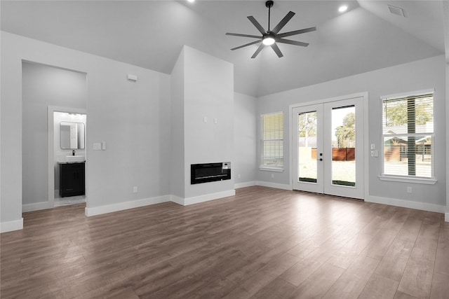 unfurnished living room with dark wood-style floors, baseboards, visible vents, and a glass covered fireplace