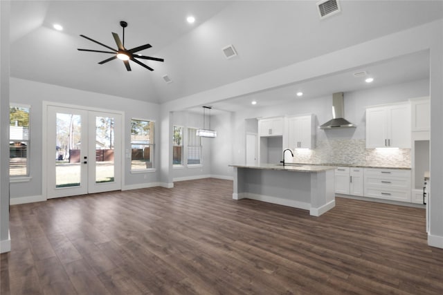 kitchen featuring a sink, visible vents, open floor plan, vaulted ceiling, and wall chimney range hood