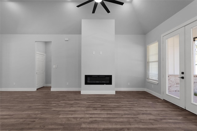 unfurnished living room featuring dark wood finished floors, heating unit, a ceiling fan, a glass covered fireplace, and vaulted ceiling