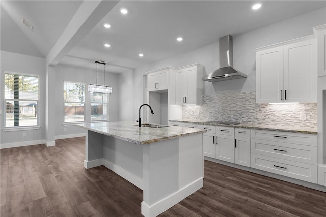 kitchen with visible vents, dark wood finished floors, decorative backsplash, wall chimney range hood, and a sink