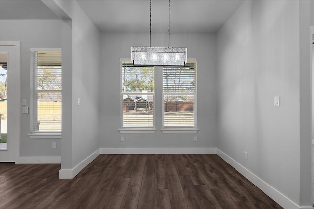 unfurnished dining area with baseboards, dark wood-type flooring, and a wealth of natural light