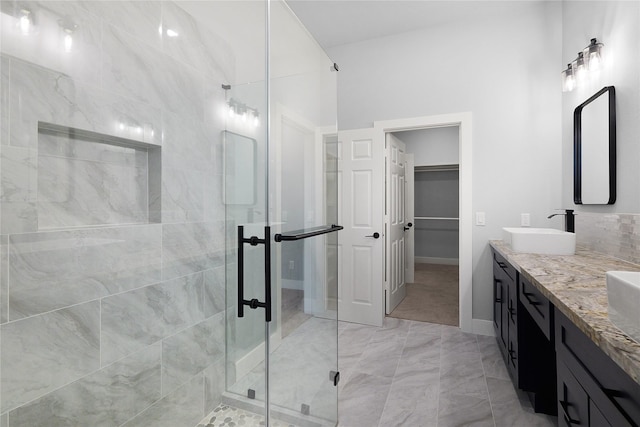 bathroom with double vanity, a stall shower, marble finish floor, a walk in closet, and a sink