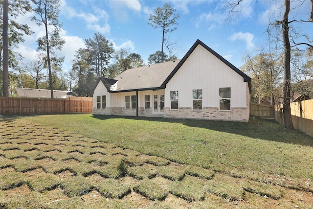 rear view of house with a fenced backyard, a lawn, and brick siding