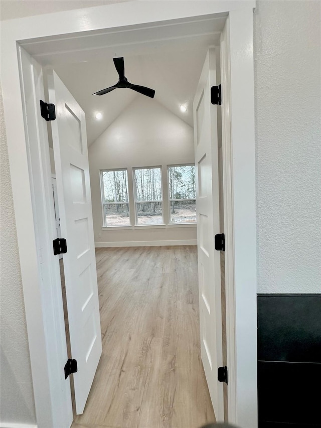 interior space with vaulted ceiling, light wood finished floors, and baseboards