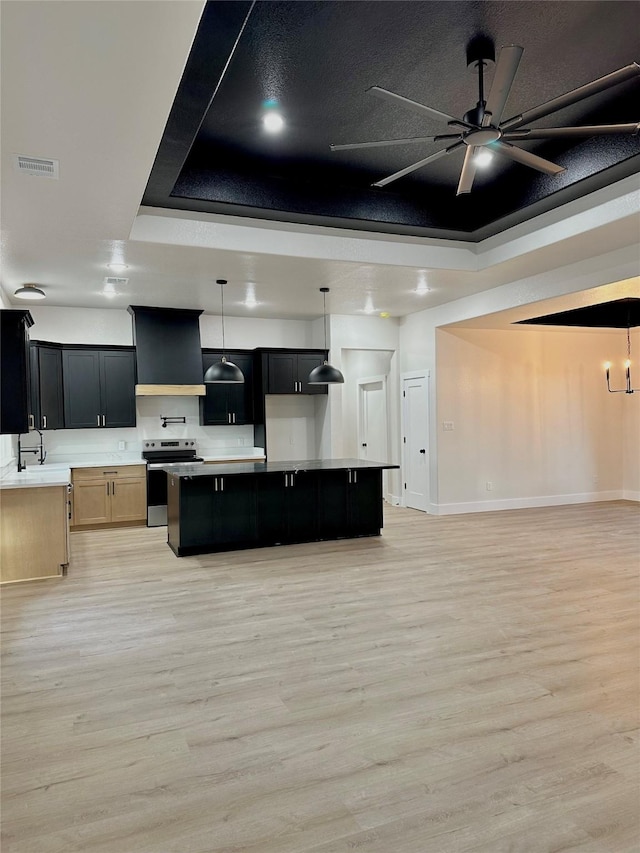 kitchen with visible vents, a raised ceiling, electric stove, and open floor plan