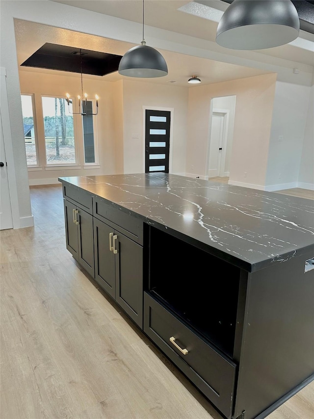 kitchen with pendant lighting, a large island, light wood finished floors, open floor plan, and dark cabinetry