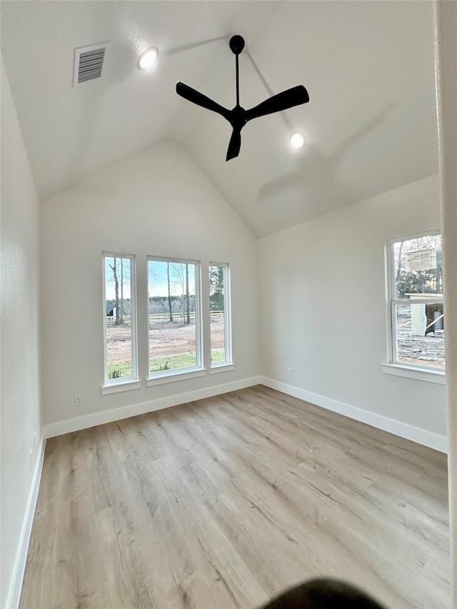 unfurnished room with vaulted ceiling, a wealth of natural light, wood finished floors, and visible vents