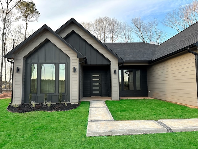 doorway to property featuring a yard, a shingled roof, and board and batten siding