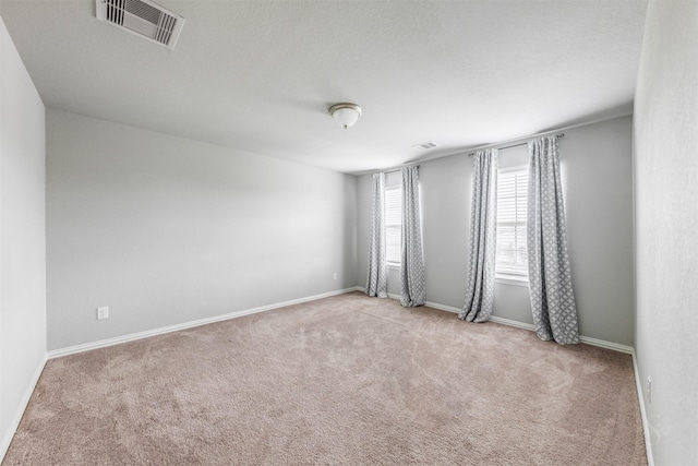 carpeted spare room with visible vents and baseboards