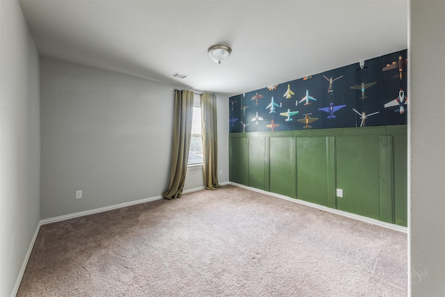 empty room with carpet floors, wallpapered walls, baseboards, and visible vents