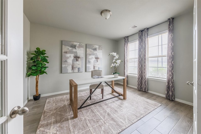 home office with wood finished floors, visible vents, and baseboards