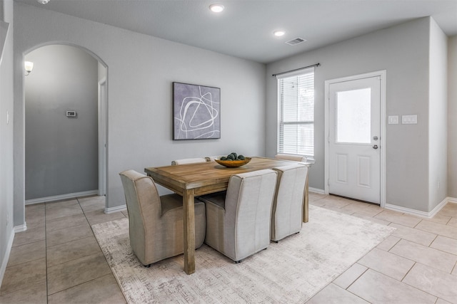 dining area with arched walkways, visible vents, baseboards, and light tile patterned flooring