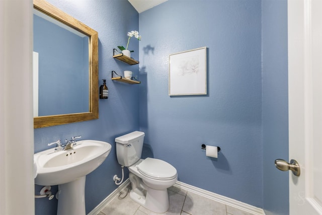 half bathroom featuring tile patterned flooring, baseboards, a sink, and toilet