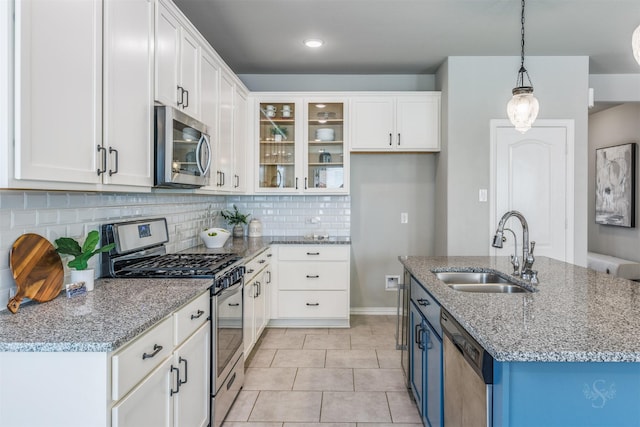 kitchen featuring appliances with stainless steel finishes, white cabinetry, a sink, and decorative backsplash