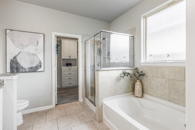 bathroom with toilet, a shower stall, tile patterned flooring, baseboards, and a bath