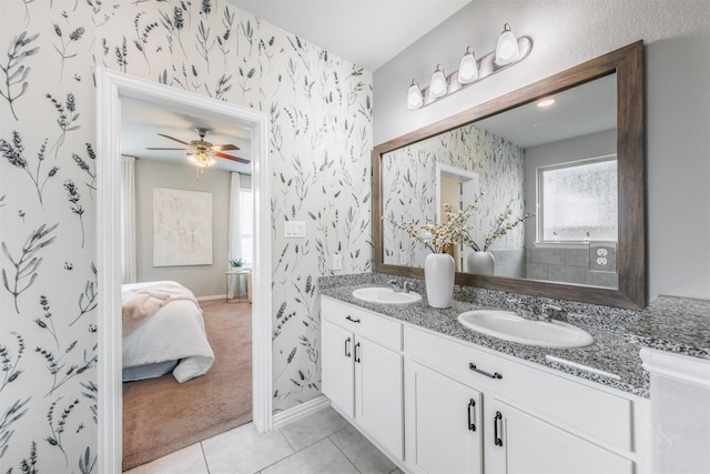 ensuite bathroom with wallpapered walls, tile patterned flooring, connected bathroom, and a sink