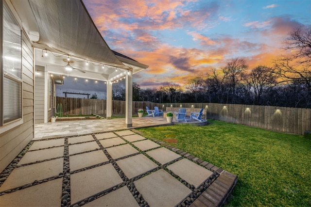 patio terrace at dusk featuring a lawn and a fenced backyard