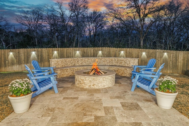 patio terrace at dusk featuring a fire pit and a fenced backyard